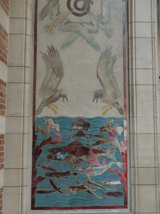 Mural/mosaico en un pilar. Se muestran peces y una medusa nadando en el mar y
gaviotas volando sobre estos.
