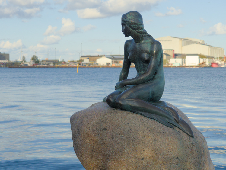 Estatua de una sirena sentada sobre una piedra.
