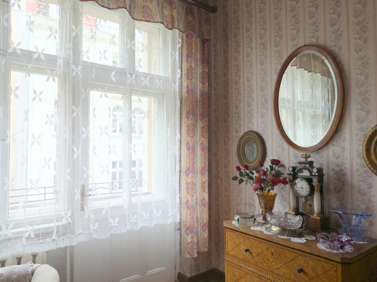 Cómoda con un espejo, algunos cuadros al rededor y varios adornos de sobremesa.
