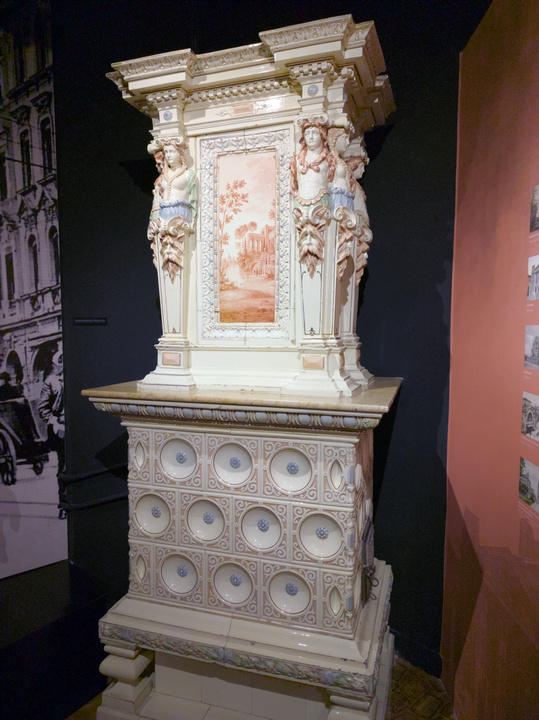 Estufa de loza adornada con estatuas y pilares.
