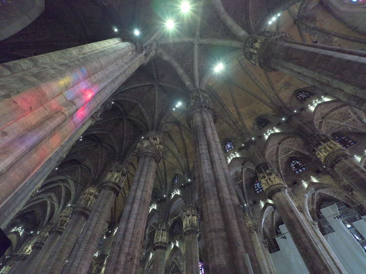 La luz que filtra a través de los vitrales tiñe los pilares.