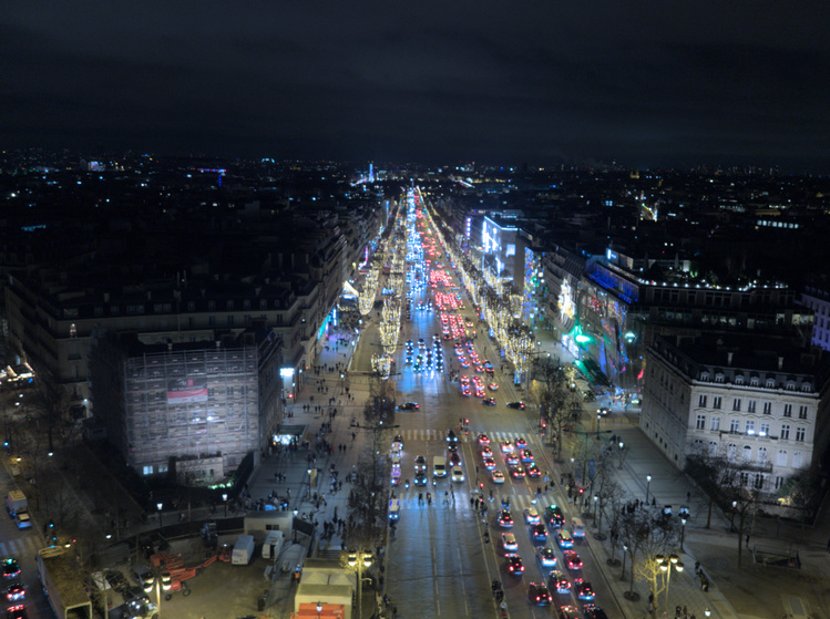 Foto nocturna de la avenida de los Campos Elíseos. Los árboles tienen luces de navidad.
