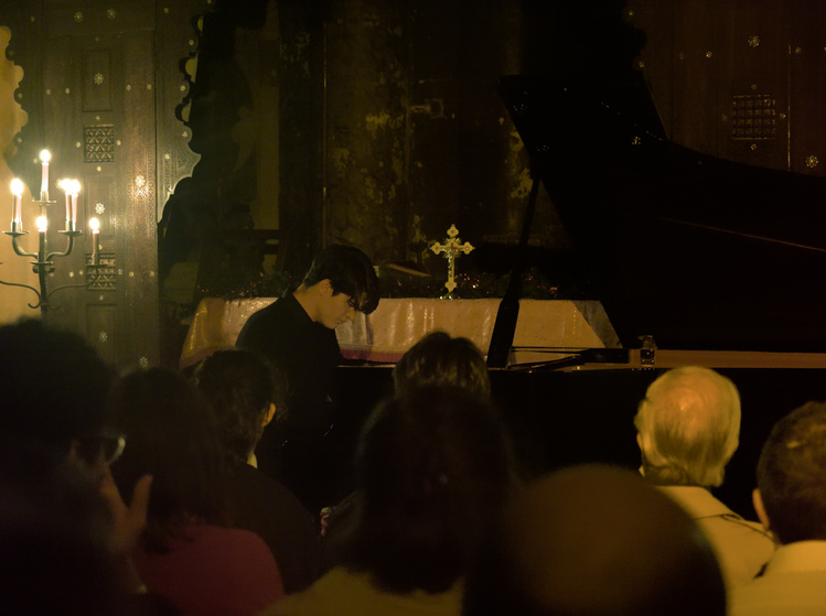 Pianista en una capilla iluminado por velas.
