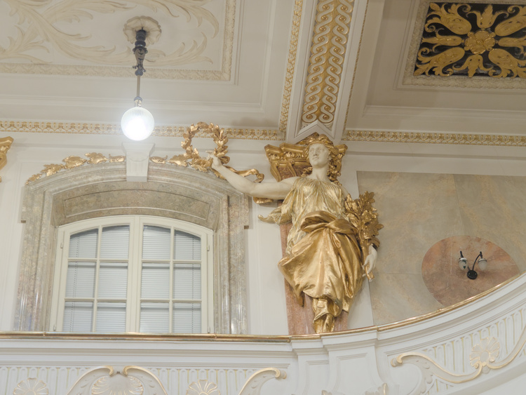 Estatua de una mujer levantando una corona de laureles.
