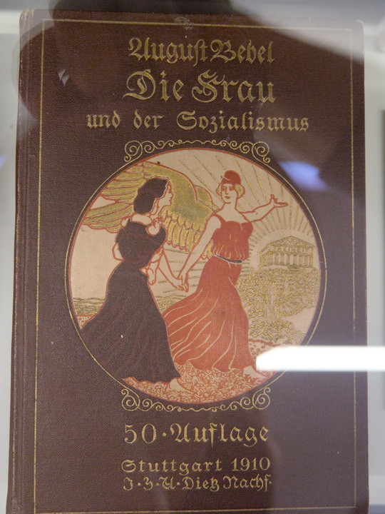 Libro de portada roja con una ilustración de una mujer con alas guiando a otra.
